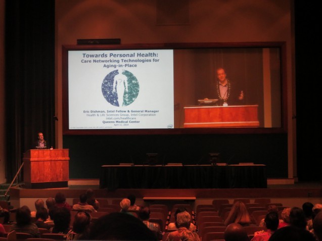 Man presenting on stage with a view of his slide deck that says "Towards Personal Health"