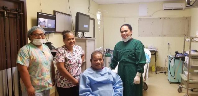 Patient in scrubs posing with hospital staff