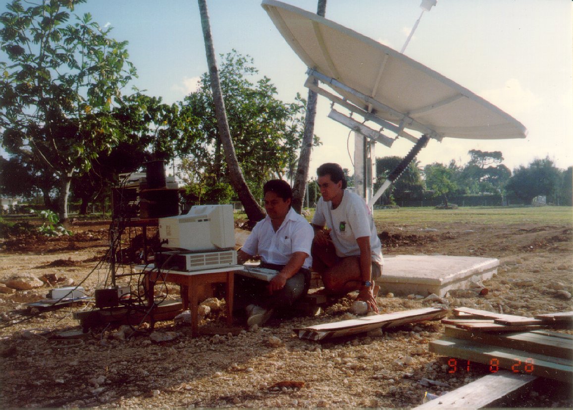 Two workers on a computer next to a satellite