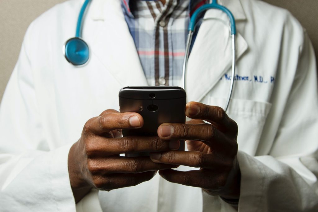 Doctor in white jacket texting on a cell phone
