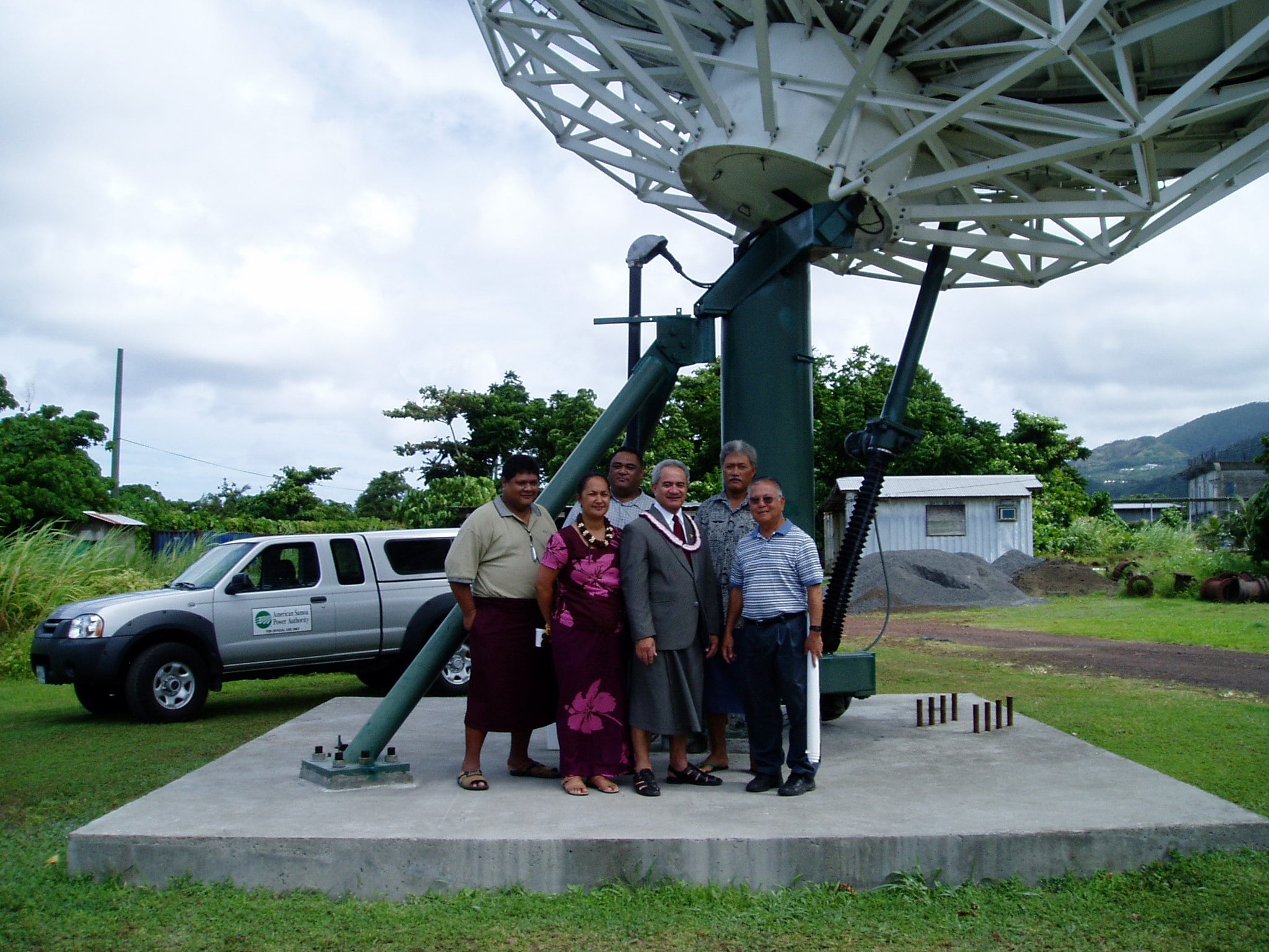 Group of people posing in front of a satellite