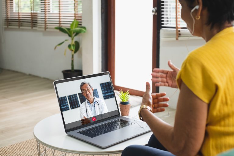 Woman in yellow shirt talking to doctor on computer